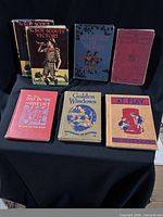 Seven vintage hardcover books standing and laying on table