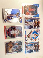 Front view of seven sleeved cards showing Maxey, Embiid, Lillard and Shai cards