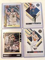 Four Nikola Jokic cards in protective sleeves showing Topps Holiday glitter, two NBA Hoops base and one serial-numbered insert