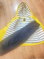 Baby GAP yellow raincoat opened to show striped lining and OshKosh black rain pants laid on top
