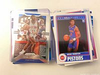 Stack of sleeved Pistons cards showing Isaiah Thomas Prizm and Ausar Thompson NBA Hoops rookie
