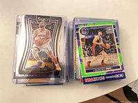 Stacks of sleeved Stephen Curry Select card atop pile and NBA Hoops stack visible