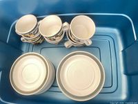 stacked coffee cups and small plates in bin