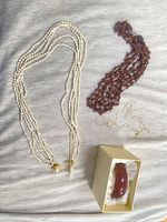 Group shot of all jewelry items laid out: pearl necklace, wood bead necklace, broken chain, two hoop earrings, boxed resin bangle