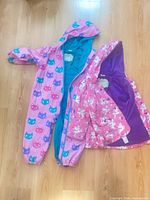 Both Hatley rain garments laid out flat showing exterior designs and linings