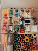 Organizer tray with embroidery floss on bobbins, small spools and cards visible