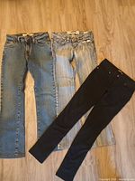 Three pairs of jeans: two blue denim, one black jegging