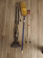 Vacuum, duster and grabber laid on floor