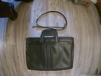 Front view of black faux leather briefcase with detachable strap placed above