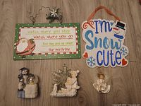 All five holiday décor pieces laid out: two hanging signs above, three figurine/ornament items below