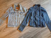 Light wash Levi's denim jacket and dark wash denim jacket laid flat on floor