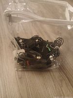 Clear bag containing assorted black cables and chargers
