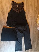 Three garments laid out: sleeveless top, skirt, pinstripe pants