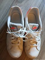 Top view of both sneakers showing white uppers laces and pink heel detail