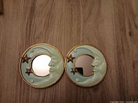 Pair of crescent moon mirrors on wood surface