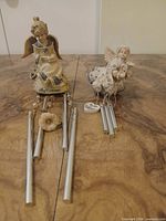 Two resin angel wind chimes side by side on table