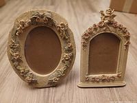 Front view of oval frame and arched plaque showing cherub and floral details