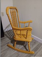 side view of honey/light oak child rocking chair showing rockers and armrest detail
