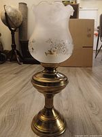 Full view of brass candle holder and frosted shade