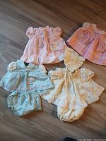 Five pastel dresses/sets laid out on floor