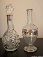 Both clear glass decanters side by side showing shapes and decorative features