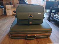Matching green Samsonite train case resting on large suitcase, shows size and style
