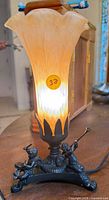Full view of lamp showing glass tulip shade and cherub base