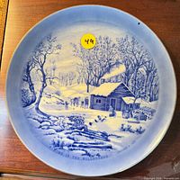 Front of blue & white plate showing winter cabin scene and title
