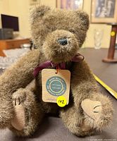 Front view of brown plush teddy bear with tag and ribbon