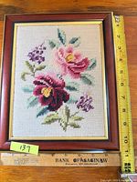 Front view of framed floral needlepoint with ruler showing dimensions