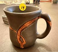 Full view of mug showing matte black finish and brown-orange accent