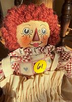 Close-up of doll’s head, face paint, red yarn hair, dress collar detail