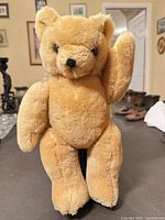 Front view of teddy bear seated with raised arm
