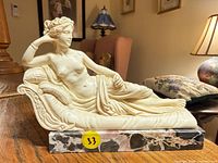 Front view of resin reclining female nude on marble base