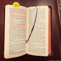 Open New Testament showing red-letter text, red page edges, purple ribbon with cross charm