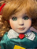 Closeup of doll face showing porcelain features, green eyes, red rosette and lace collar