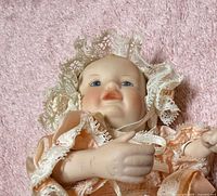 Close frontal view of doll’s head, torso, dress and bonnet