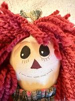 Close-up of doll face showing red yarn hair and embroidered features