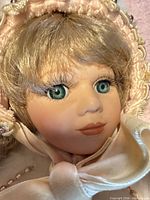 Close-up of doll face showing painted features, glass eyes, bonnet detail