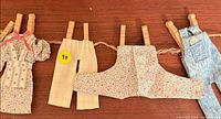 Overall view of four miniature garments hanging on twine with clothespins