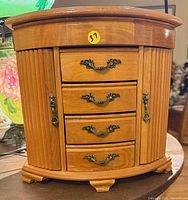 Front view of oak jewelry box showing four drawers and ornate hardware