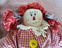Close head view showing yarn hair, embroidered face, lace collar