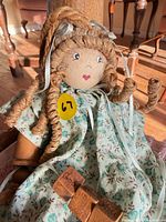 Close-up of doll’s head, hair, dress and wooden limbs