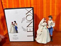 Front view of figurine beside branded box