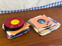 Both stacks of 45 RPM records on wood surface