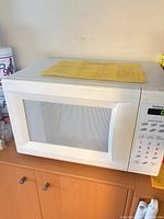 Front view of Galaxy white countertop microwave on cabinet