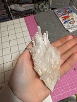 Hand holding white bladed crystal cluster showing overall form