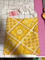 Full view of yellow floral diamond print bag front with white strap