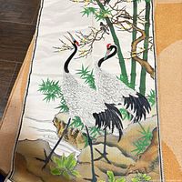 Full view of silk brocade tapestry showing two cranes, bamboo, rocks and water