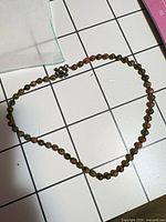 Full view of necklace laid flat showing bead color and clasp